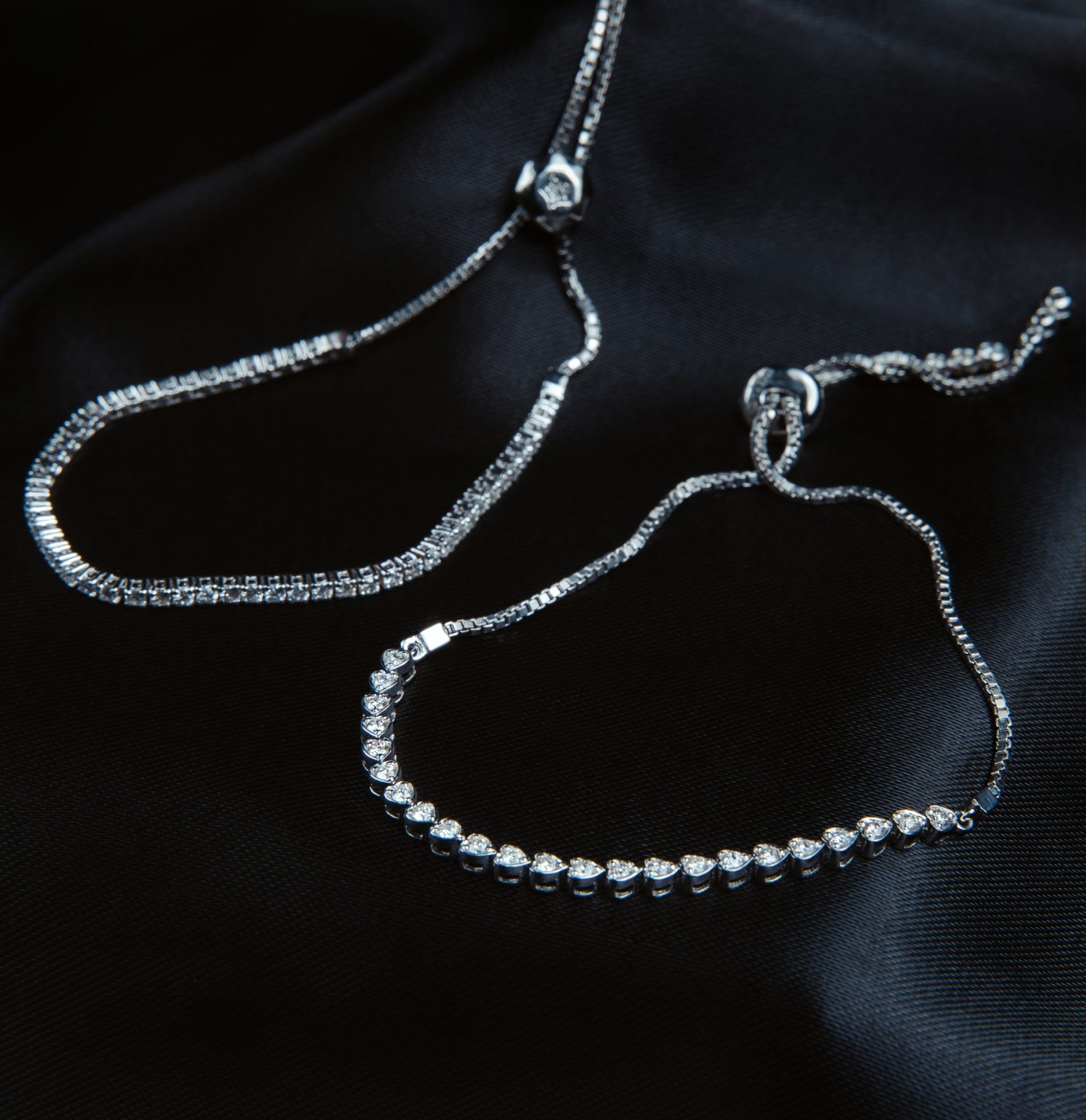 side view of silver bracelets with diamonds on black background